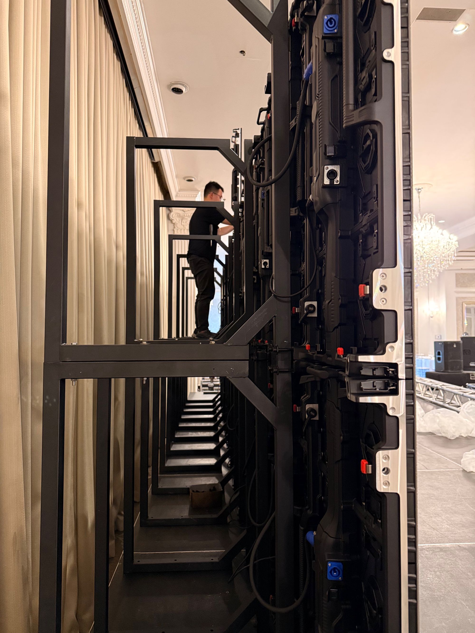 SPARK technician building an LED wall on ground support behind a ballroom stage