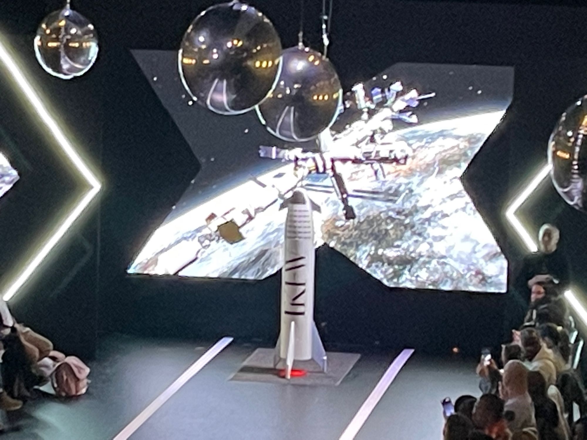 A rocket set piece on the runway in front of an angled star-shaped LED wall showing a space station